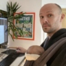 A snug dressing gown with a sleeping baby in a sling, at a standing desk.